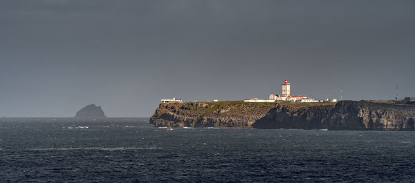 Lighthouse by sea against sky