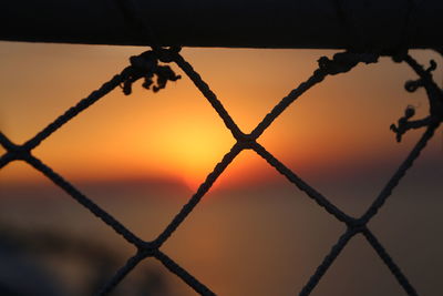 View of sunset seen through chainlink fence