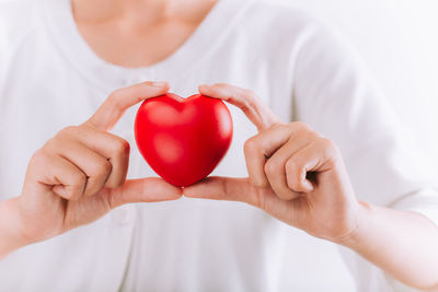 Midsection of woman holding red heart shape