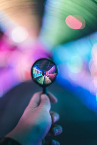 Cropped hand holding magnifying glass in front of illuminated decoration