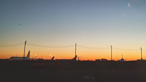 Silhouette electricity pylons against clear sky during sunset