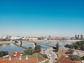 High angle view of river and buildings against clear blue sky