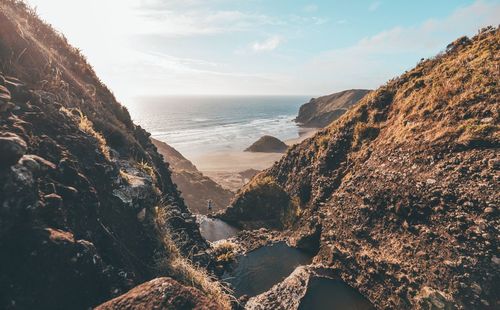 Scenic view of sea by mountains against sky