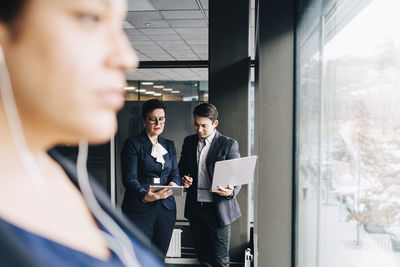 Senior businesswoman showing digital tablet to colleague in conference room at office