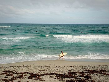Female surfer walking on calm beach