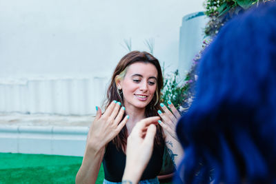 Happy young women playing patty cake in backyard