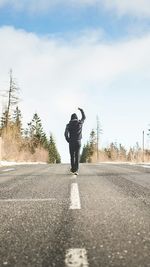 Rear view of man standing on road against sky