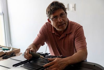 Man installing the wall base for the television, it is a smart tv, adjusting with screwdriver