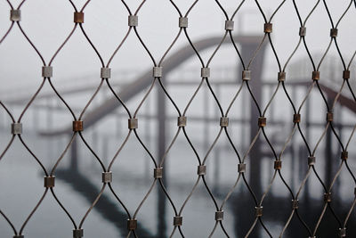 Full frame shot of chainlink fence against bridge
