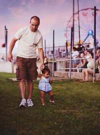 Father and daughter holding hands while walking in amusement park