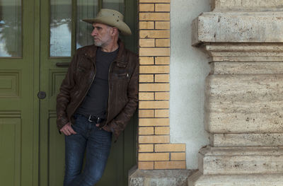 Portrait of adult man in cowboy hat standing on doorway