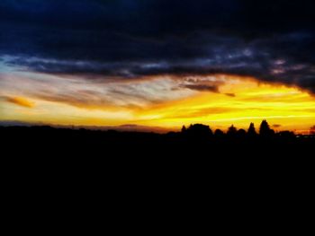 Scenic view of silhouette landscape against dramatic sky during sunset