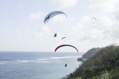 People paragliding over sea against sky