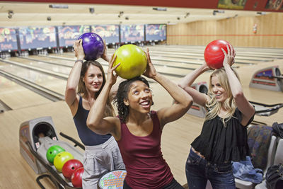 Three young woman with bowling balls on top of their head.