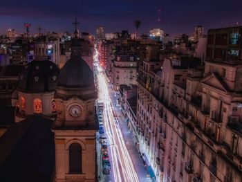 Light trails on road amidst buildings at dusk in city