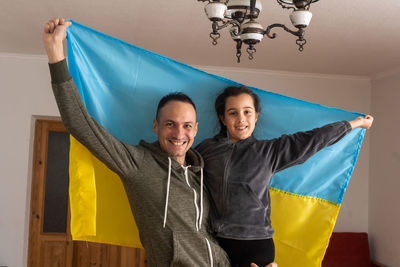 Portrait of father and son holding ukrainian flag