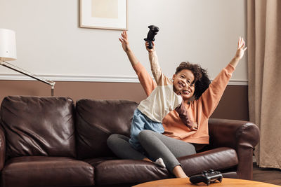 Full length of smiling man sitting on sofa at home