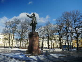 Statue by bare trees against sky during winter