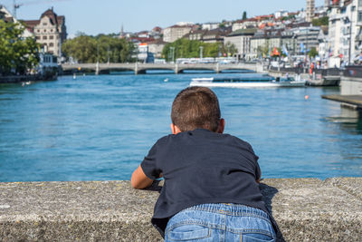 Rear view of boy standing by retaining wall