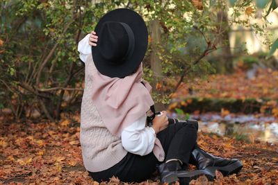 Midsection of woman sitting in park during autumn