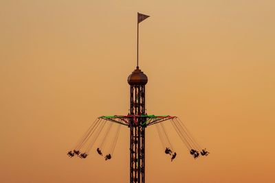 Low angle view of illuminated ferris wheel against sky during sunset