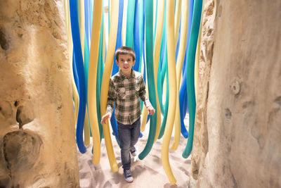 Portrait of boy standing against tubes on sand