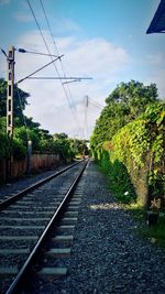 Railway tracks by trees against sky