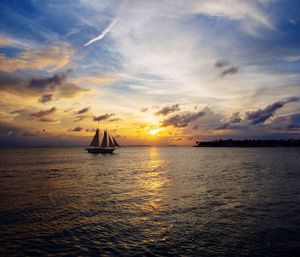 Sailboat sailing on sea against sky during sunset