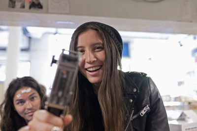 Portrait of smiling young woman holding camera