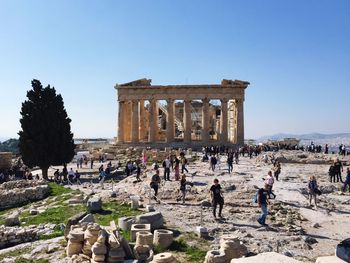 People at parthenon against clear sky