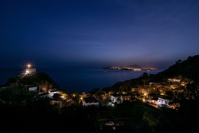 High angle view of townscape by sea against sky at night