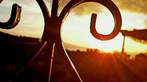 Close-up of metallic structure on field against sky during sunset