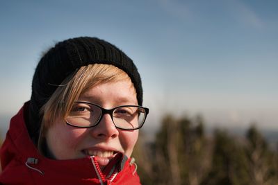 Portrait of young woman wearing eyeglasses against sky