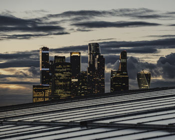 Modern buildings in city against sky during sunset