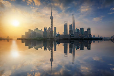 Reflection of buildings on river in city during sunset