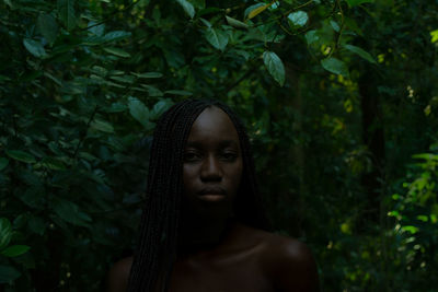 Portrait of shirtless young woman standing in forest