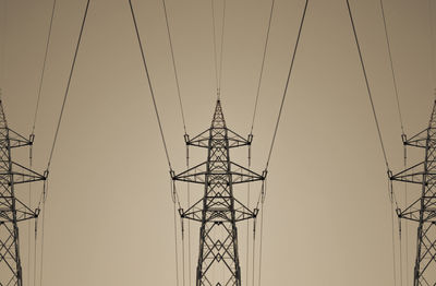 Low angle view of electricity pylon against clear sky