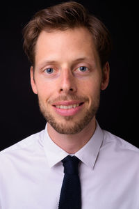 Portrait of smiling young man against black background