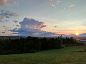 Scenic view of field against sky at sunset