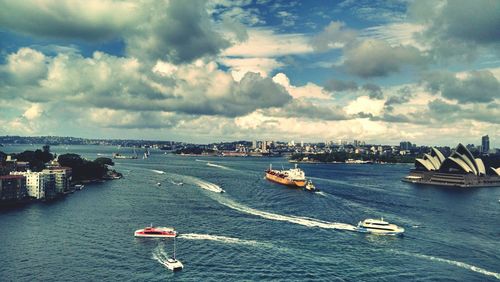 Boats sailing in sea against sky in city