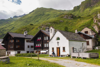 Houses on field by mountain against sky