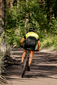 Rear view of man riding bicycle on street