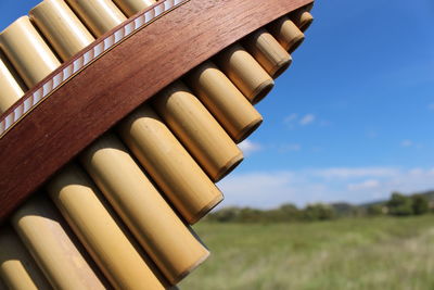 Close-up of stack of wood on field against sky