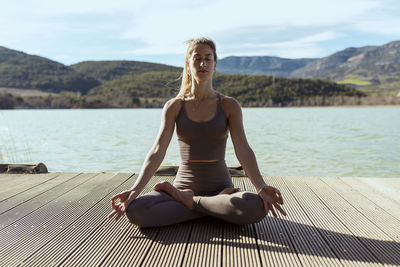 Woman with eyes closed meditating while sitting in lotus position on sunny day