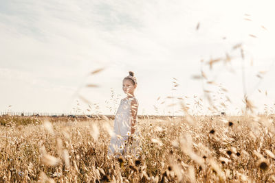 Girl standing on field against sky