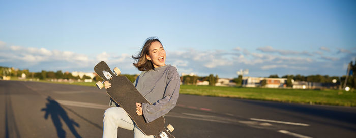 Portrait of young woman standing against sky