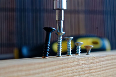 Close-up of screwdriver fixing nail in wood