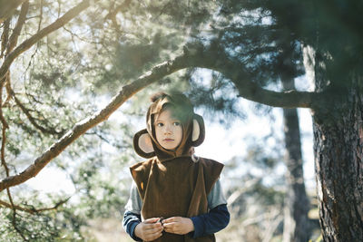 Thoughtful girl in monkey suit standing by tree at yard