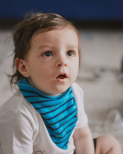 Close-up of cute baby wearing bib and looking with surprise at the television 