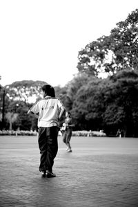 Rear view of man walking against trees